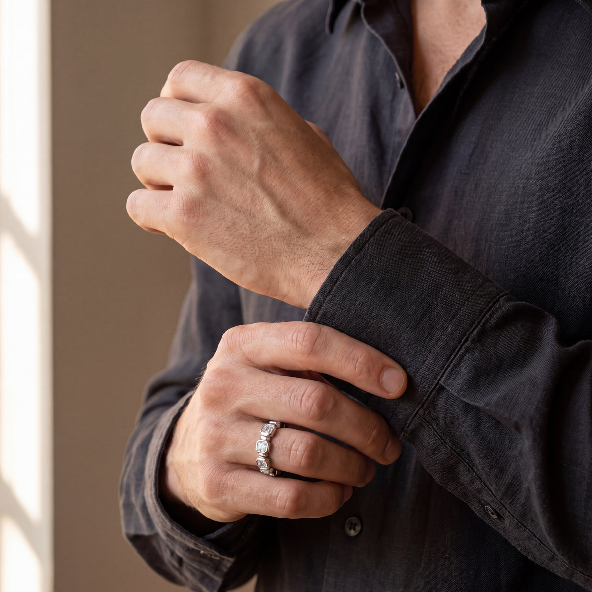 Men’s white gold Asscher-cut diamond eternity band, shown on the hand in a lifestyle photo with a dark shirt cuff.