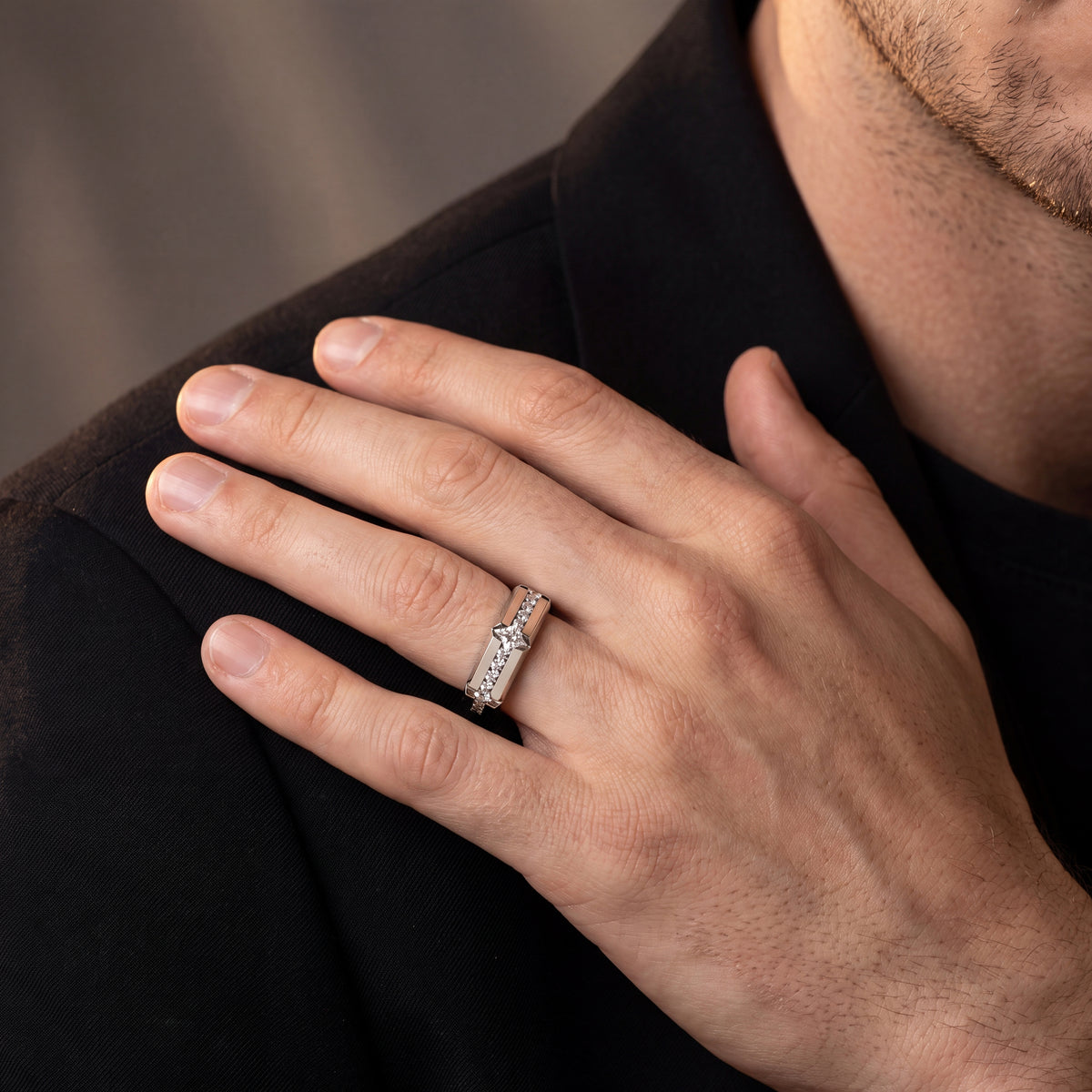 Men’s white gold geometric diamond ring with angular diamond accents, shown on a hand against a dark background.
