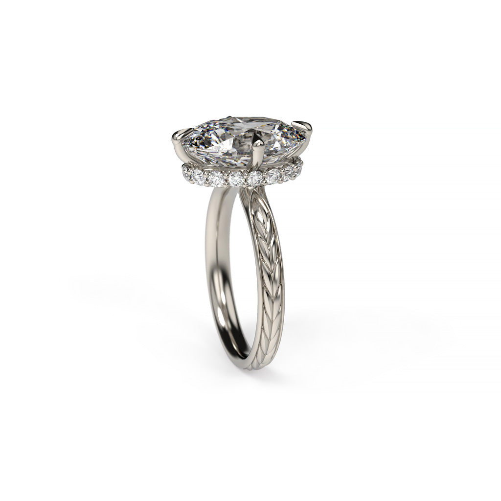 Angled view of a white gold oval diamond hidden halo engagement ring with compass prongs, diamond accents, and a spikelet-inspired shank.