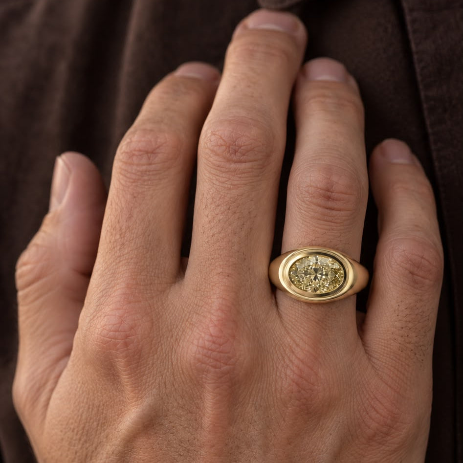Top view of an oval yellow diamond set horizontally in a stepped bezel on hand
