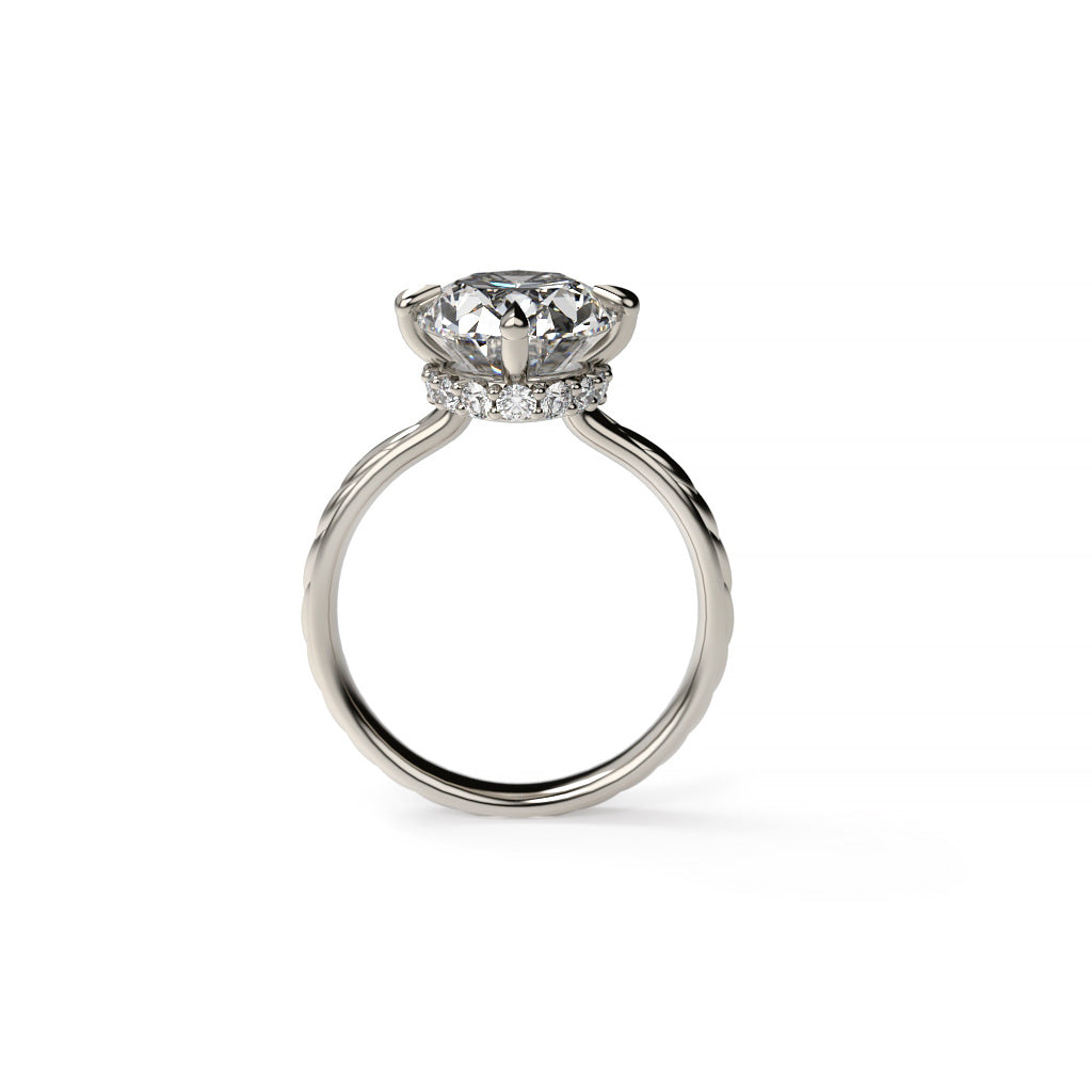 Side profile of a white gold oval diamond hidden halo engagement ring with compass prongs, diamond accents, and a spikelet-inspired shank.